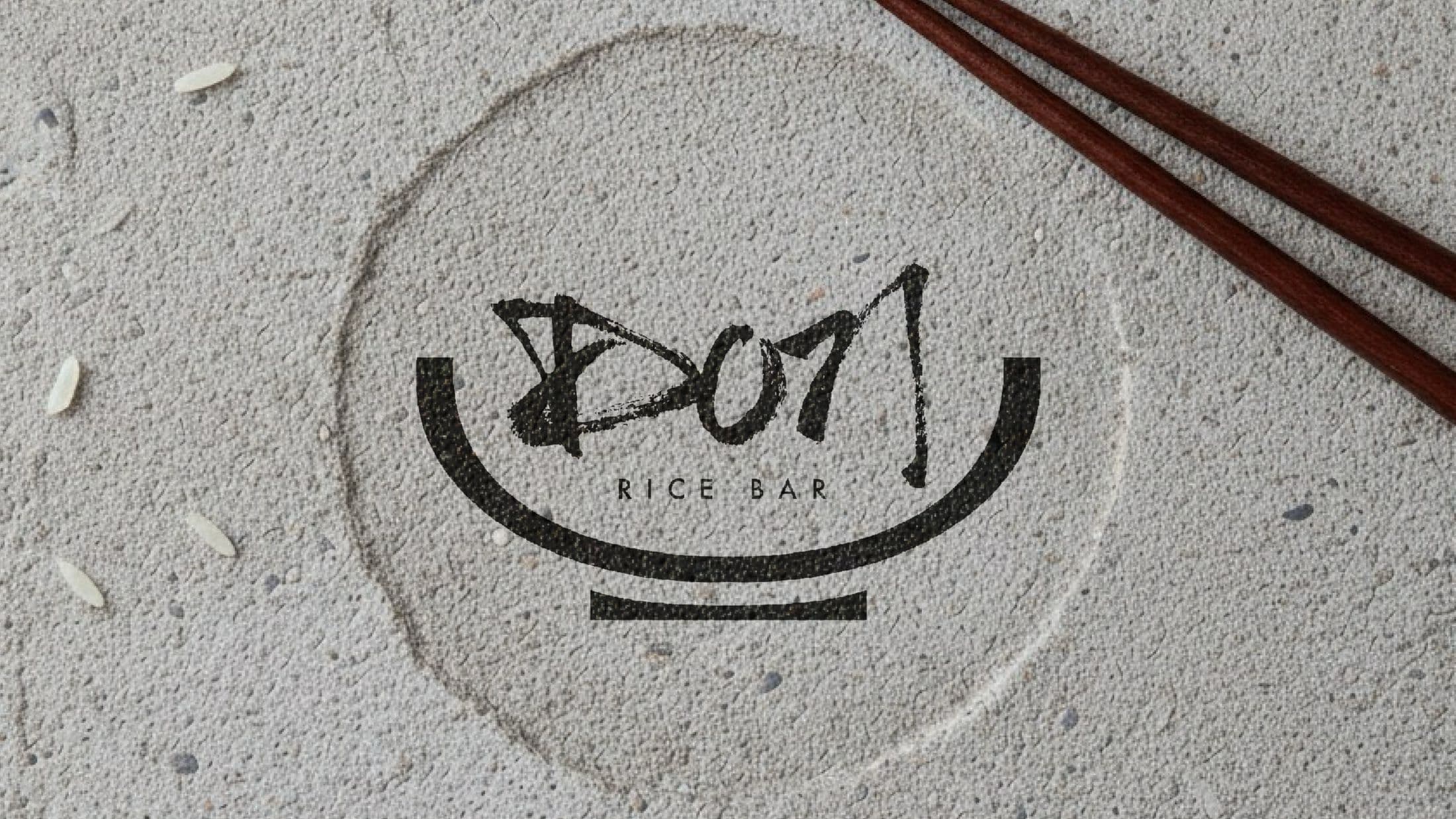 Don Rice Bar's hand-brushed logo stamped on textured paper beside chopsticks and grains of rice